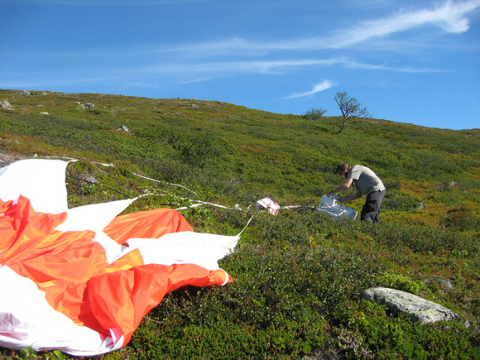 Researcher untangles a orange and white scientific balloon in a field from 2017
